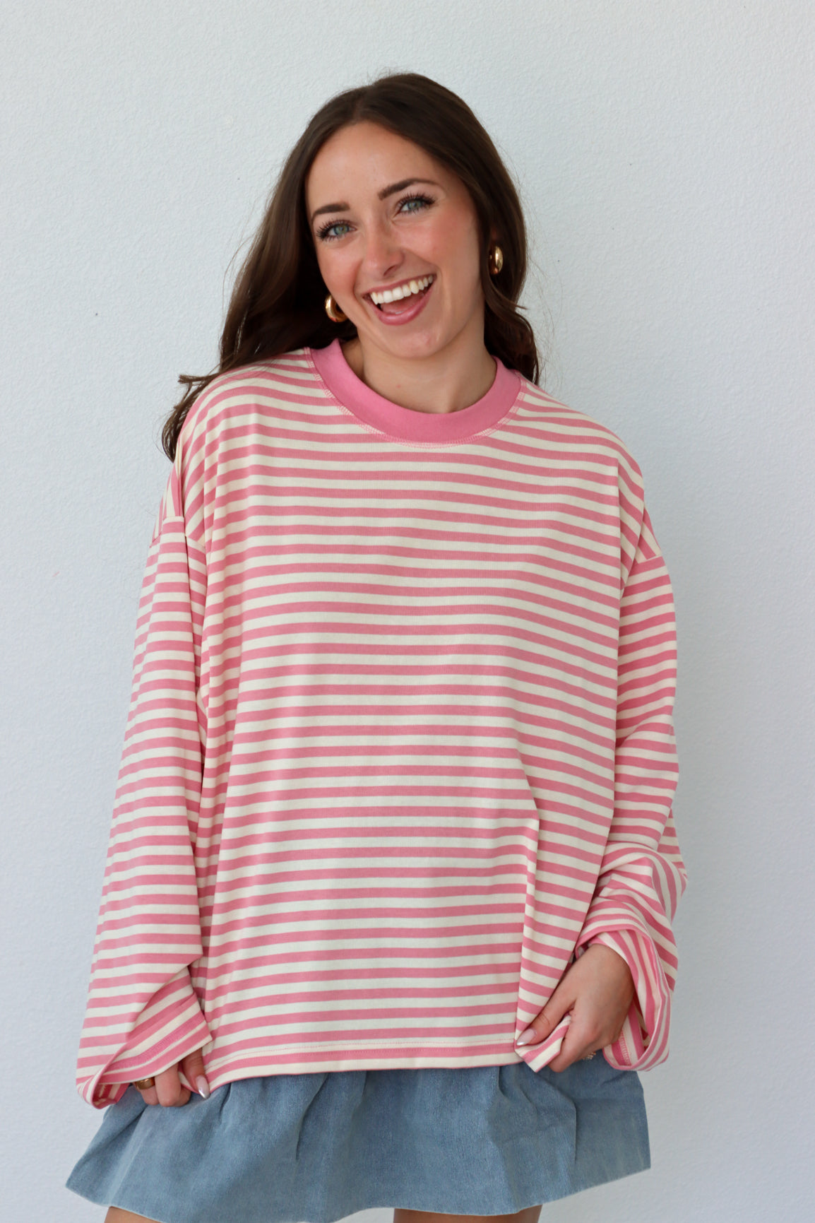 Woman wearing a pink and white striped shirt with a blue skirt against a white background