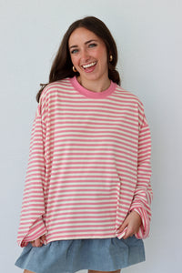 Woman wearing a pink and white striped shirt with a blue skirt against a white background
