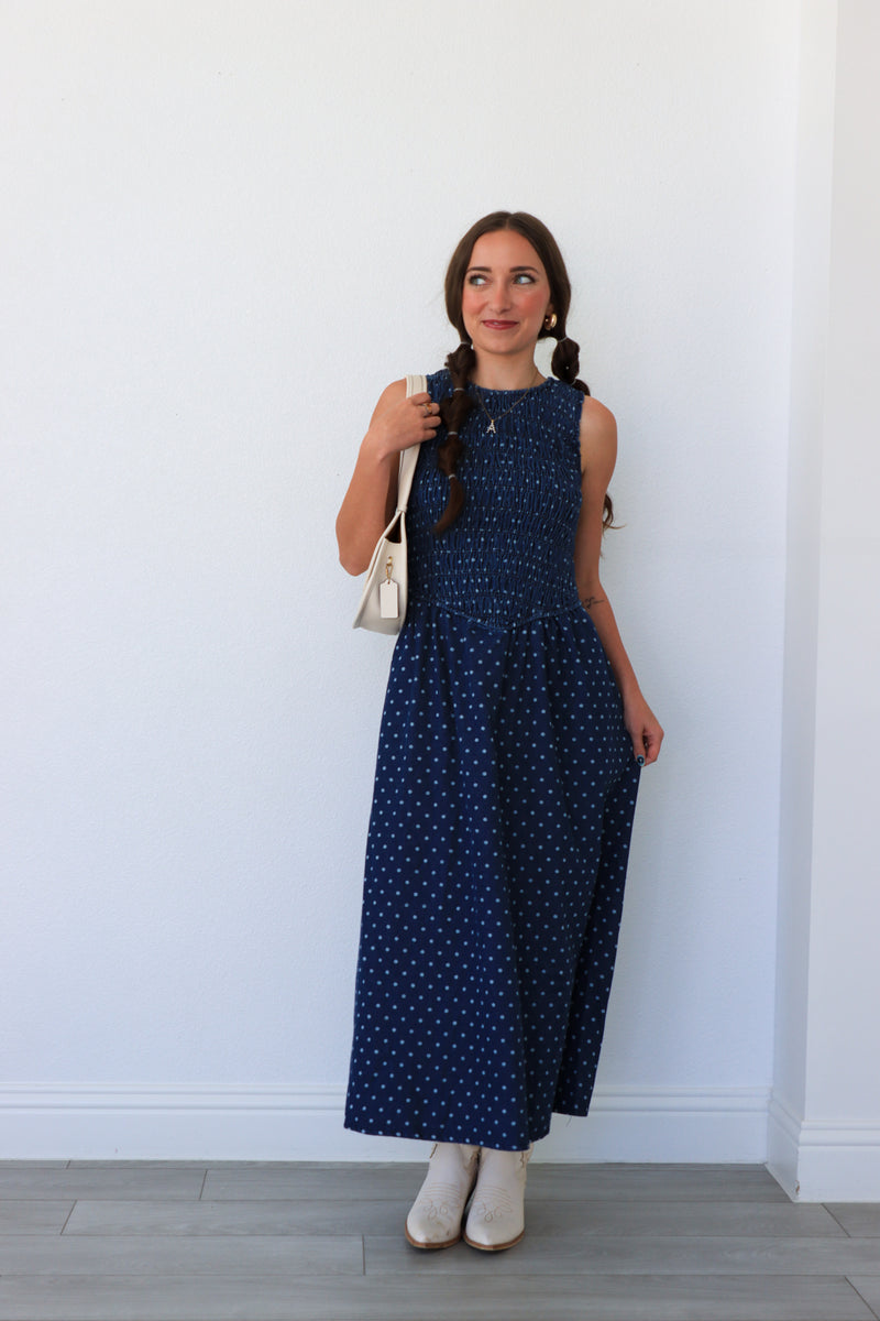 Woman wearing a blue polka dot dress against a white wall