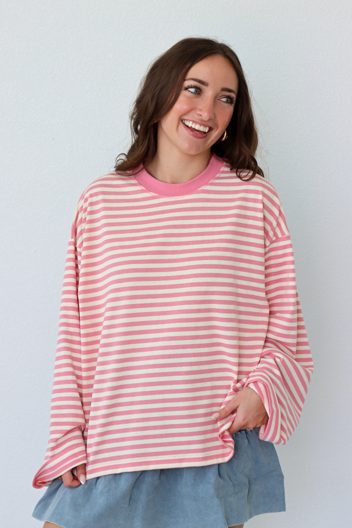 Woman wearing a pink and white striped shirt against a plain background