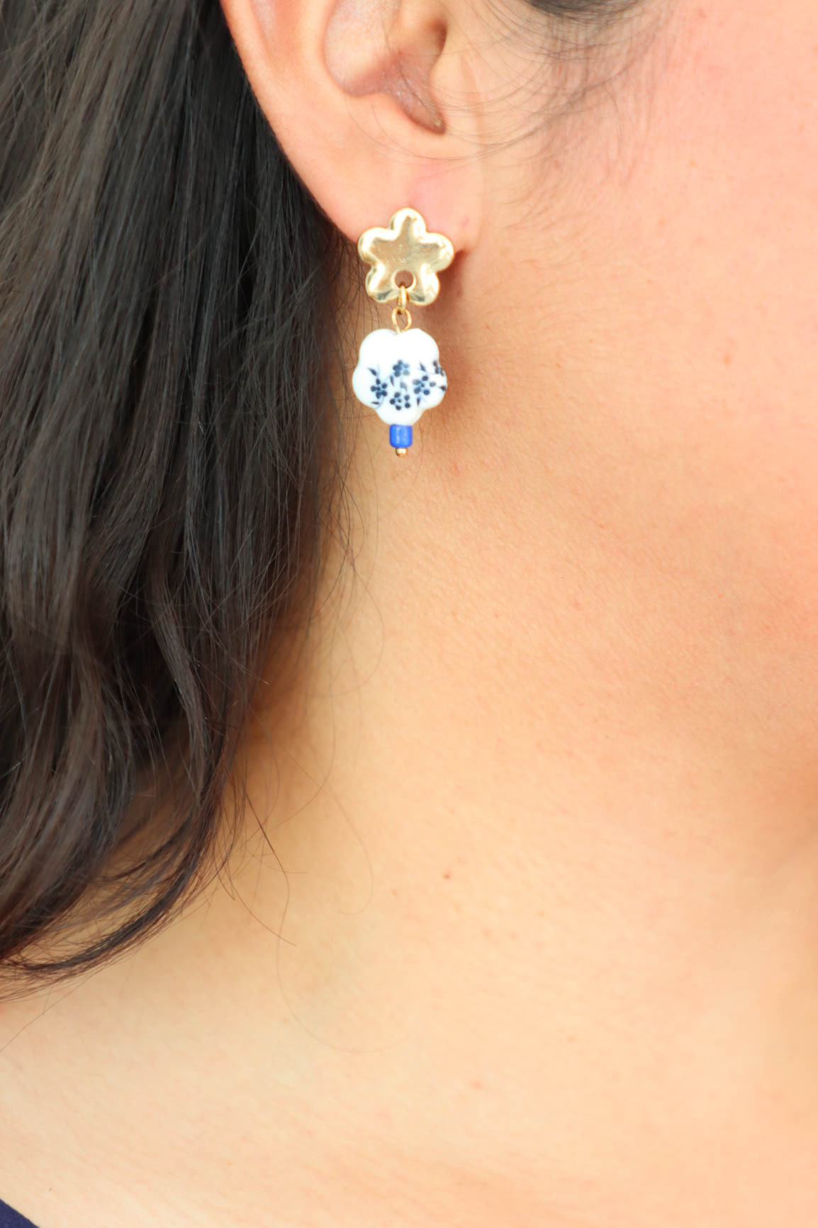 girl wearing gold earrings with white and blue porcelain charm