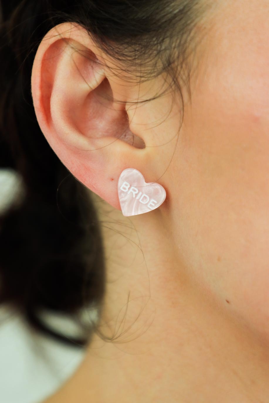 girl wearing pink stud heart earrings with "bride" letters