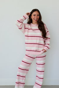 Woman wearing pink and white striped set against a white background