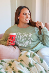 girl wearing light green crewneck sweatshirt with "be merry and bright" graphic
