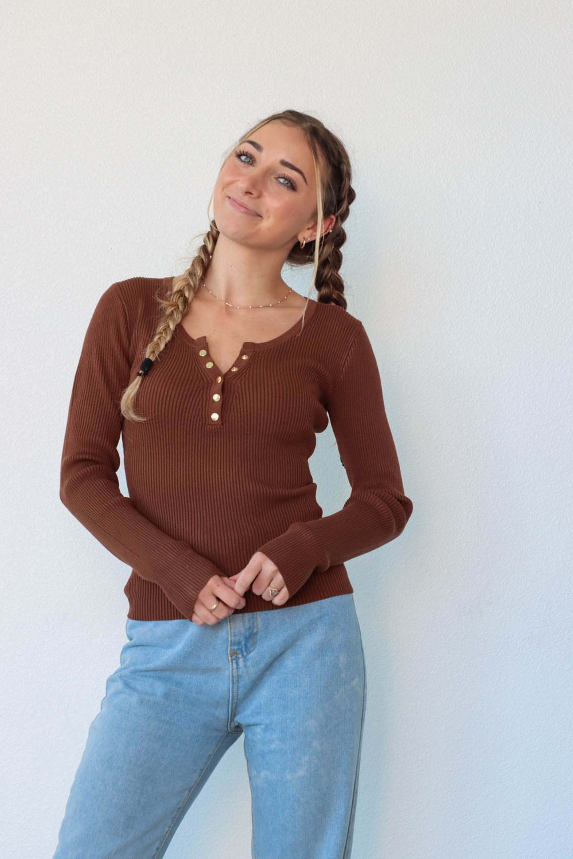 girl wearing chocolate brown long sleeve top with snap detailing
