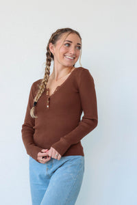 girl wearing chocolate brown long sleeve top with snap detailing