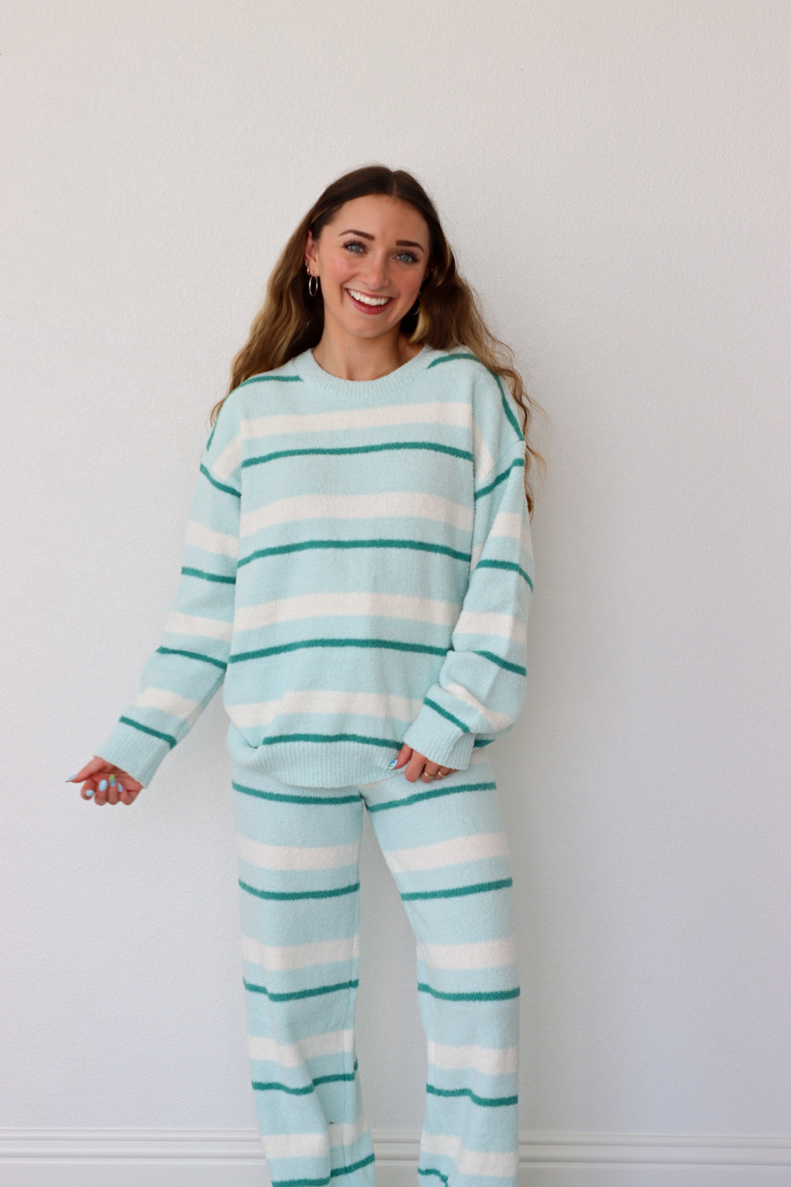 Woman wearing a light blue and white striped set against a plain background