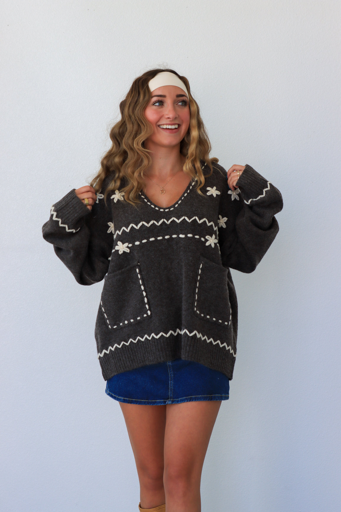 Woman wearing a dark sweater with white patterns against a plain background