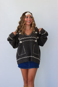 Woman wearing a dark sweater with white patterns against a plain background