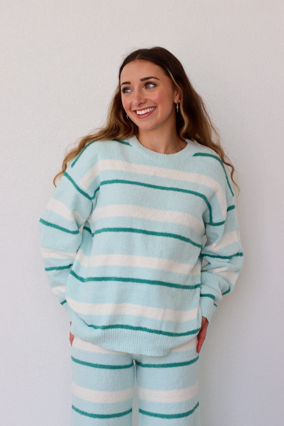 Woman wearing a light blue and white striped sweater against a plain background