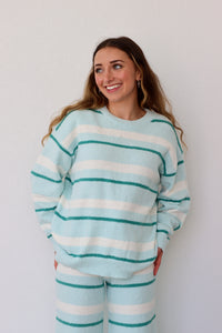 Woman wearing a light blue and white striped sweater against a plain background