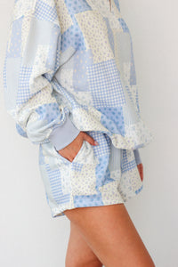 Person wearing a patchwork quilt as a garment on a plain background