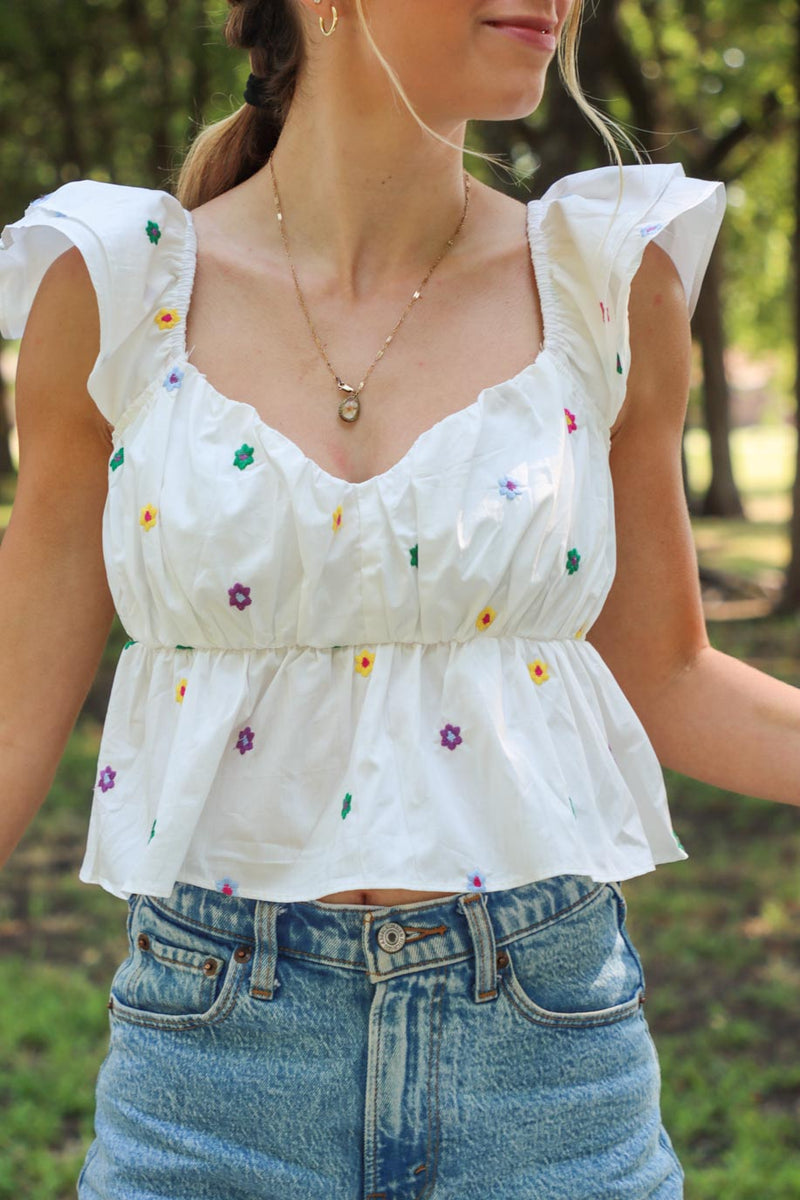 girl wearing white puff sleeve top with multicolored embroidered flowers