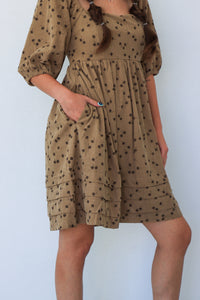 Brown dress with black pattern worn by a person against a white background