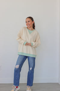 girl wearing cream longsleeve top with light blue detailing