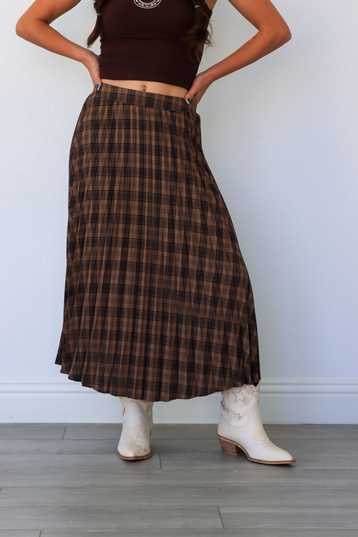 Person wearing a plaid skirt and white boots against a plain background