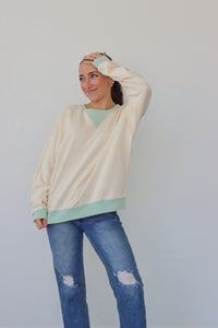 girl wearing cream longsleeve top with light blue detailing