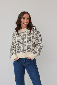 girl wearing cream sweater with black floral knit pattern
