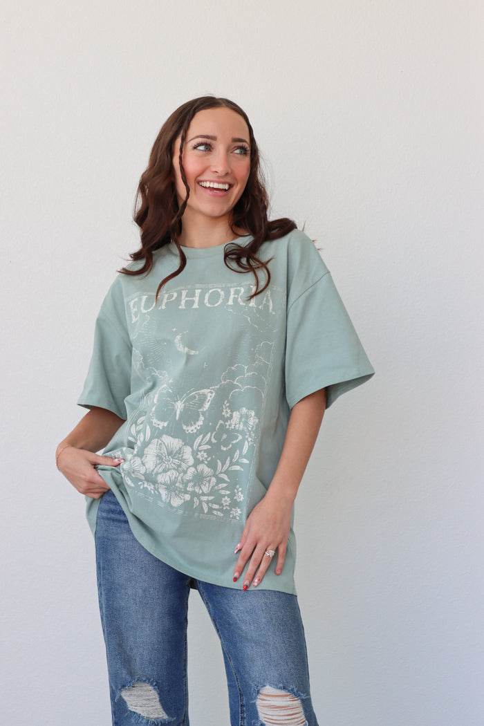 girl wearing sage green t-shirt with a "euphoria" graphic