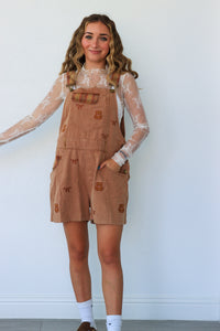 woman wearing tan teddy bear short overalls