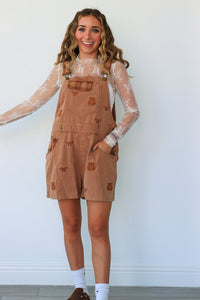 woman wearing tan teddy bear short overalls