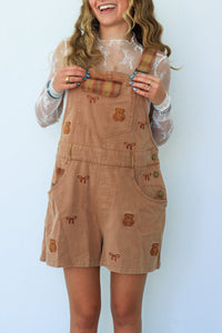 woman wearing tan teddy bear short overalls