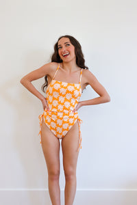 girl wearing orange floral one piece swimsuit