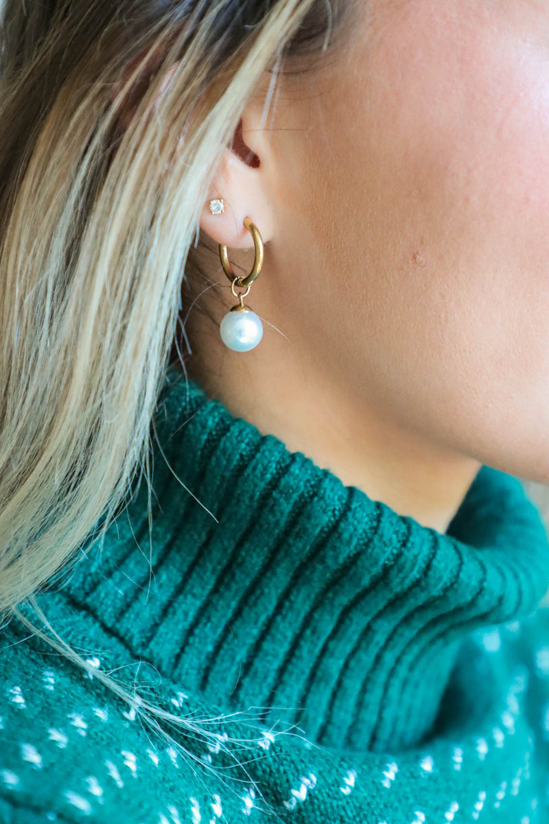 girl wearing hold huggie hoop earrings with a pearl charm