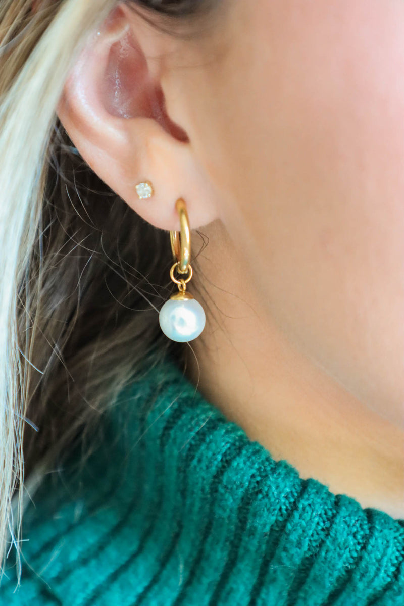 girl wearing hold huggie hoop earrings with a pearl charm