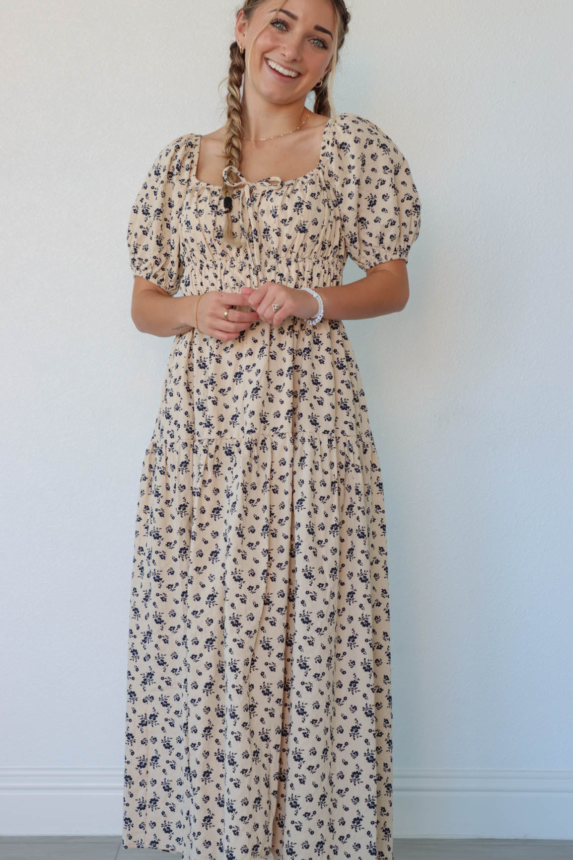 girl wearing cream long dress with navy floral pattern and puffed sleeves