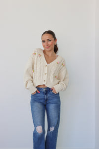 girl wearing cream cardigan with pink crochet flowers