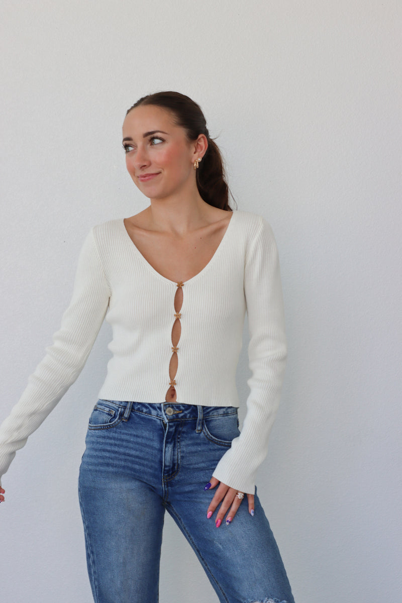 girl wearing cream cardigan with flower buttons