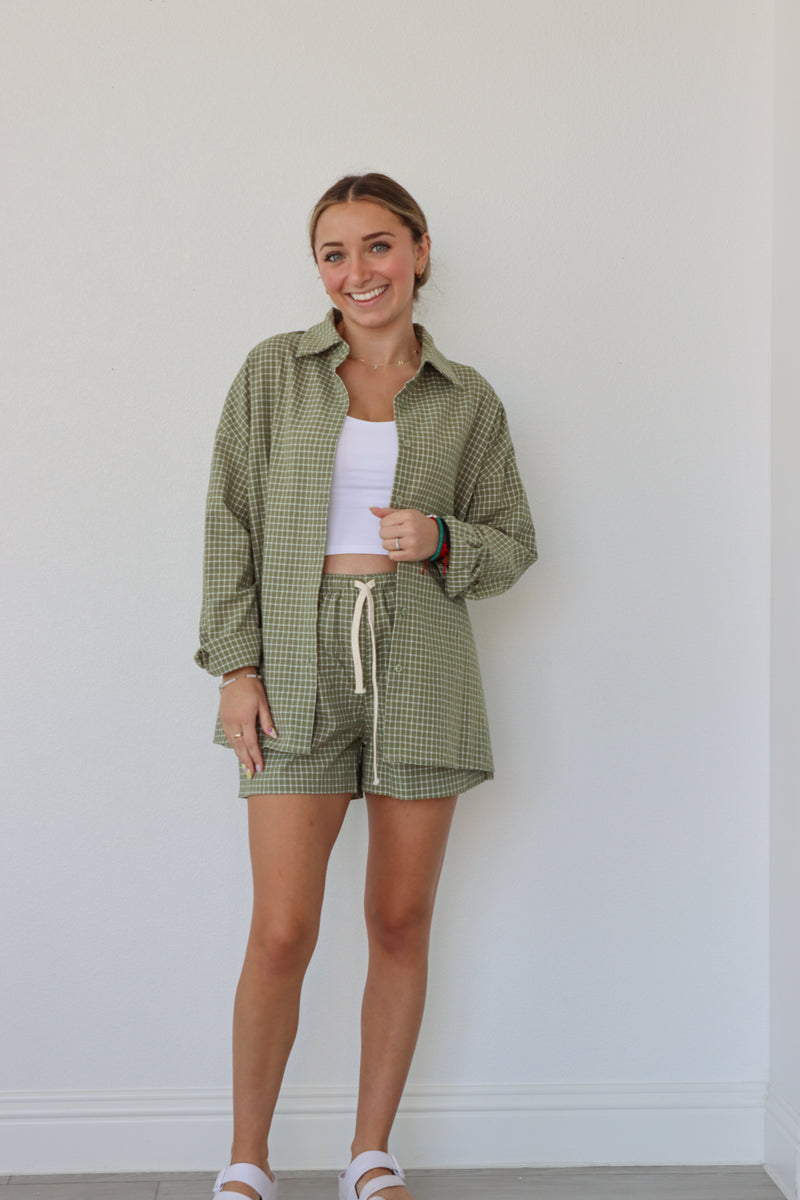 girl wearing sage green checkered set; button down shirt and shorts