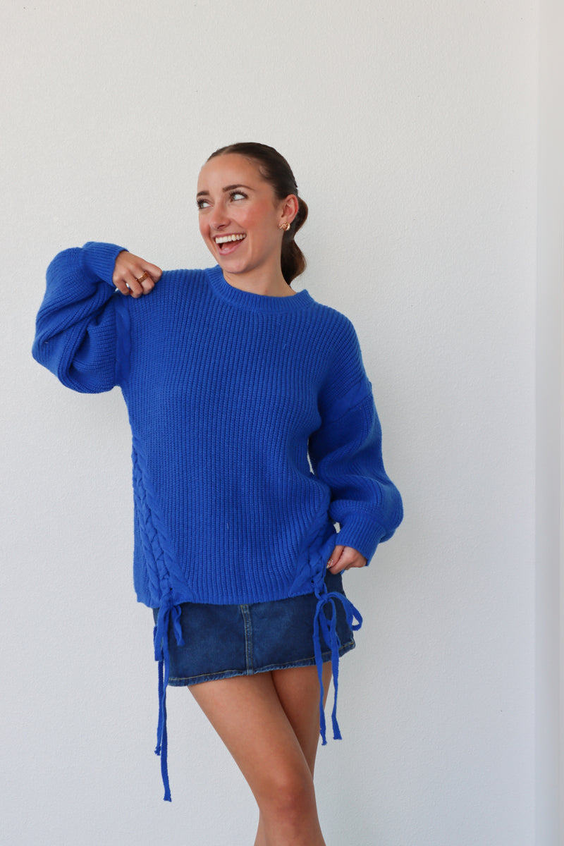 Woman wearing a blue sweater and denim skirt against a white background