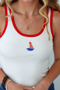 White tank top with red trim featuring a sailboat design, worn by a person.