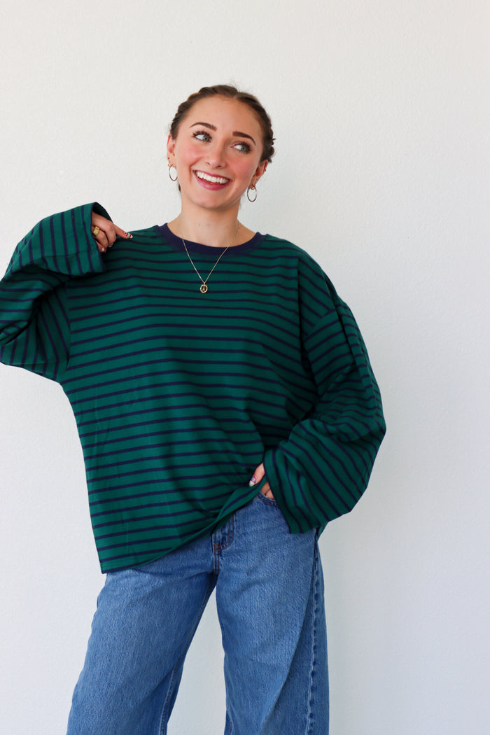 Woman wearing a green striped sweater and blue jeans against a white background