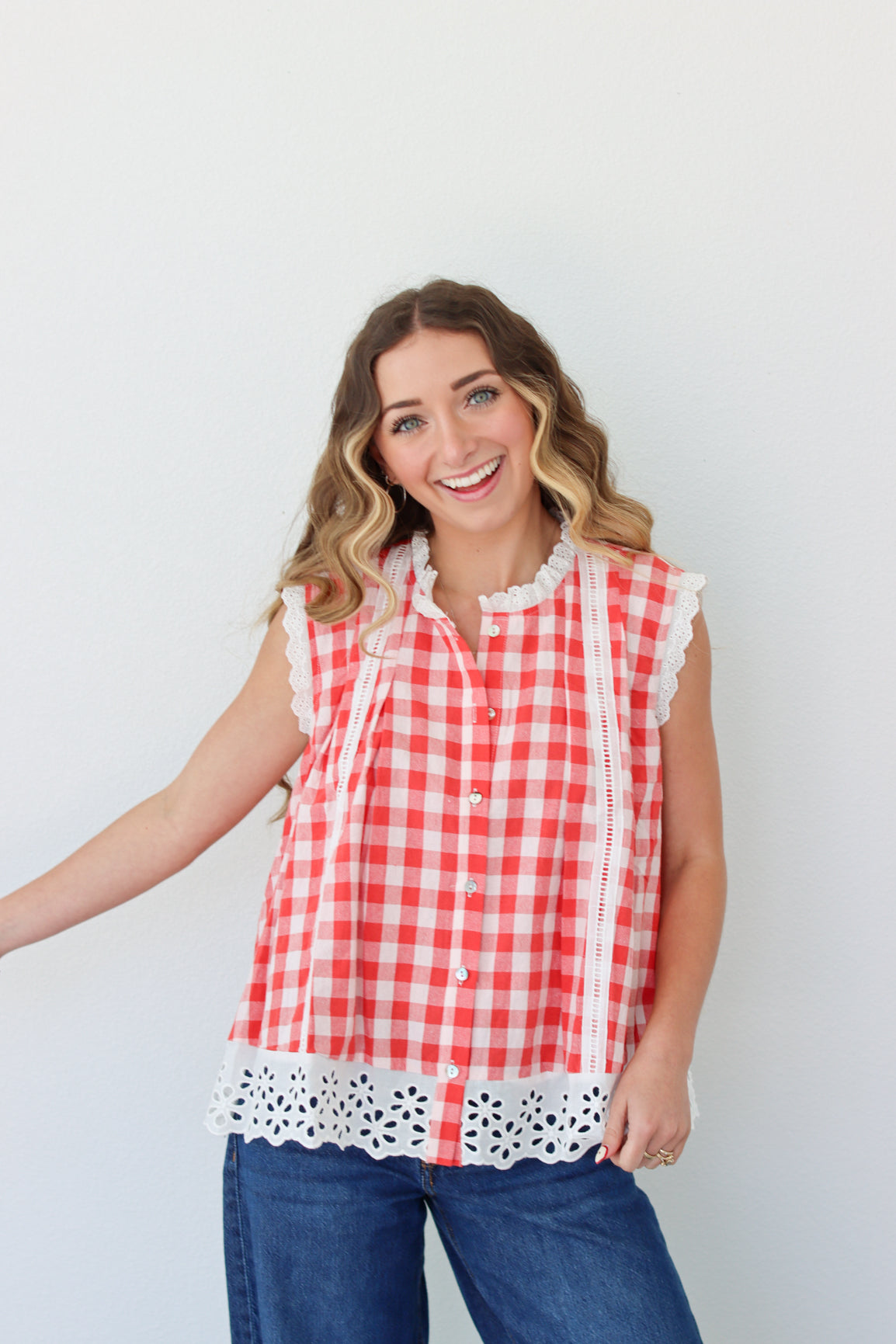 Woman wearing a red and white checkered blouse with lace details against a white background
