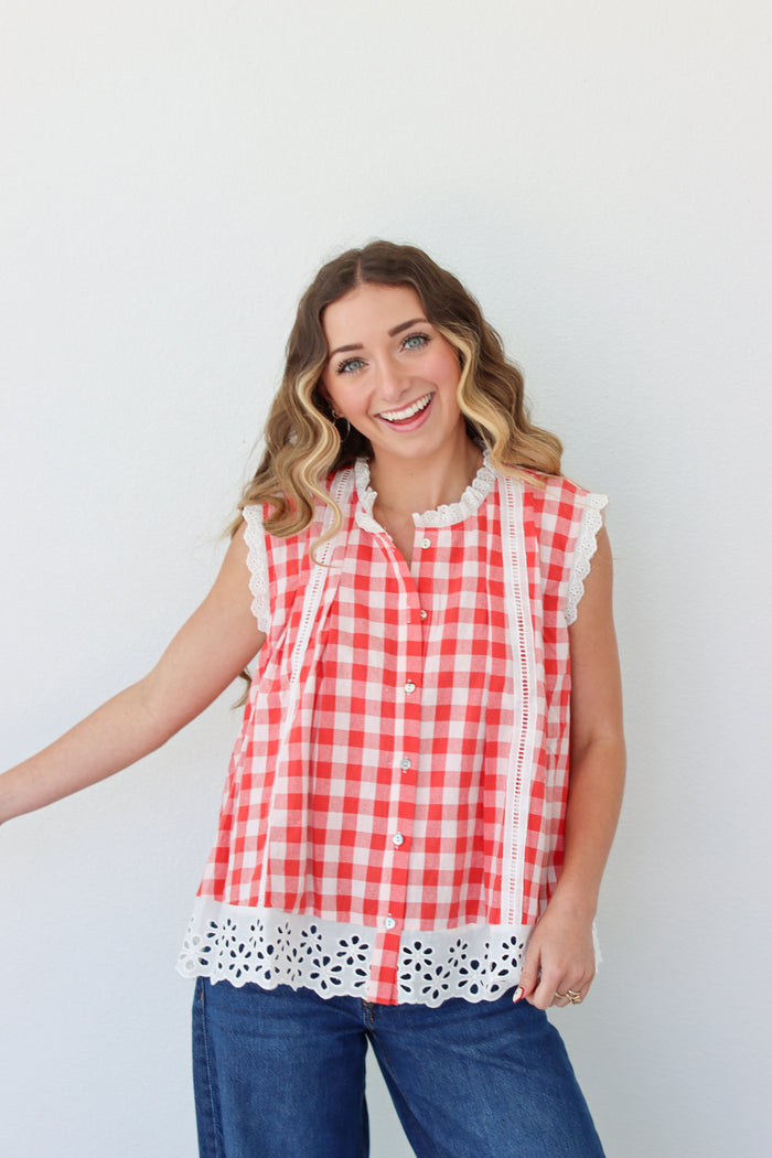 Woman wearing a red and white checkered blouse with lace details against a white background