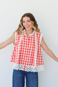 Woman wearing a red and white checkered sleeveless top with lace trim against a plain background