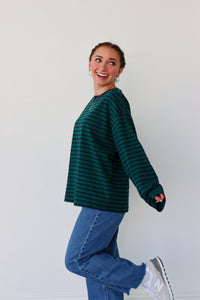 Person wearing a green striped sweater and blue jeans against a white background
