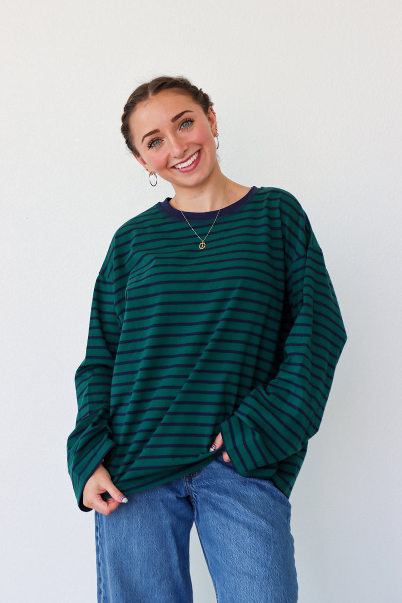 Woman wearing a green striped sweater and blue jeans against a white background