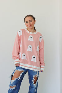 girl wearing pink crewneck with ghost patches