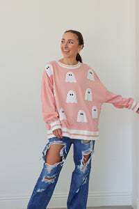 girl wearing pink crewneck with ghost patches