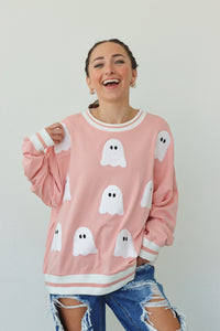 girl wearing pink crewneck with ghost patches