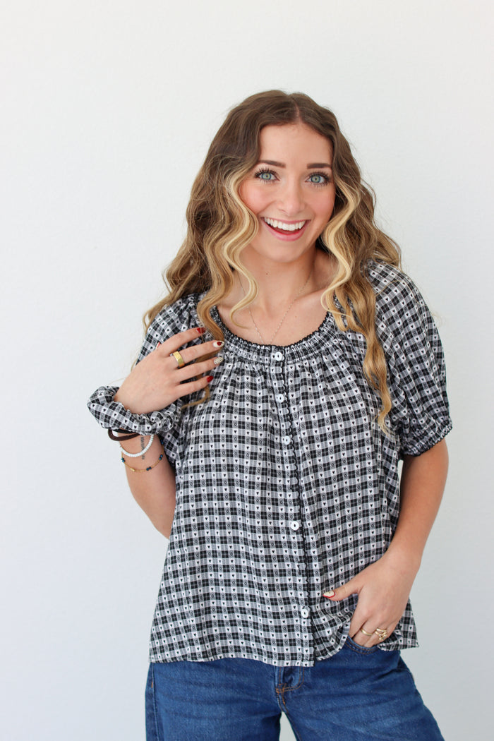 Woman wearing a black and white checkered shirt with blue jeans on a plain background
