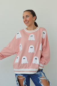 girl wearing pink crewneck with ghost patches