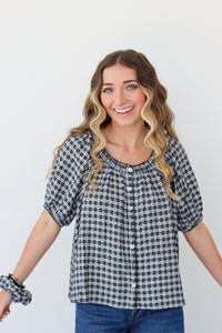 Woman wearing a black and white checkered shirt with blue jeans on a plain background