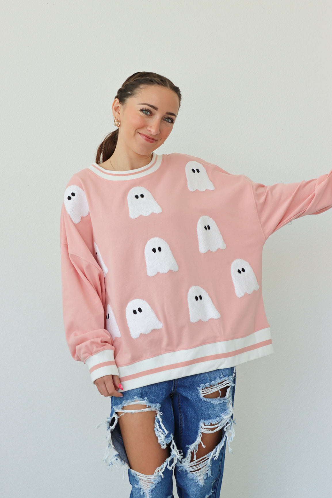 girl wearing pink crewneck with ghost patches