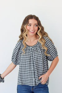 Woman wearing a black and white checkered shirt with blue jeans on a plain background
