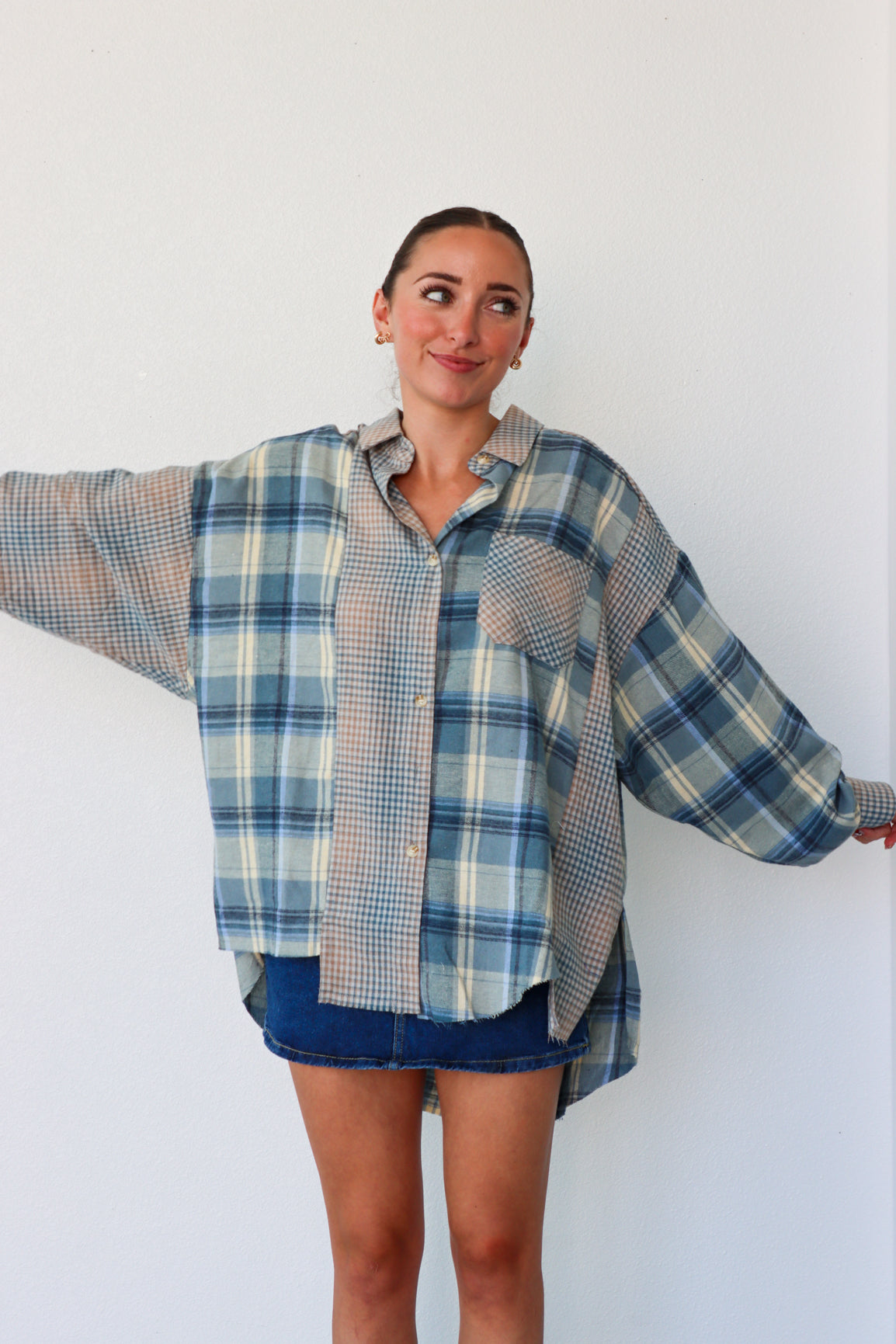Woman wearing a plaid shirt over a dress against a white background